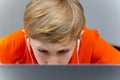 A boy wearing white headphones and using a laptop works hard while sitting at home for training Royalty Free Stock Photo