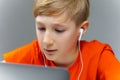 A boy wearing white headphones and using a laptop works hard while sitting at home for training Royalty Free Stock Photo