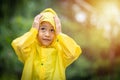 A boy wearing a yellow raincoat. Happy Asian little child having fun playing with the raindrops. A boy looking up at the sky and