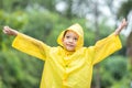 A boy wearing a yellow raincoat. Happy Asian little child having fun playing with the raindrops. A boy looking up at the sky and