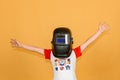 A boy in a welding mask waves his hands in different directions, on a yellow background