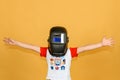 A boy in a welding mask waves his hands in different directions, on a yellow background