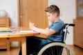 Boy in wheelchair doing homework and using tablet pc Royalty Free Stock Photo