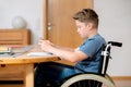 Boy in wheelchair doing homework and using tablet pc Royalty Free Stock Photo