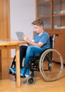 Boy in wheelchair doing homework and using tablet pc Royalty Free Stock Photo