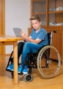 Boy in wheelchair doing homework and using tablet pc Royalty Free Stock Photo