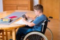 Boy in wheelchair doing homework and using tablet pc Royalty Free Stock Photo