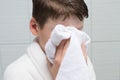 Boy, in a white bathrobe, in the bathroom, wipes his face with a towel, after washing Royalty Free Stock Photo