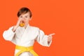 Boy in white kimono drinks water. Kid practicing karate on color background. Kid sport concept Royalty Free Stock Photo
