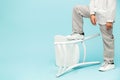 Boy in white linen suit posing against blue background with his foot on an inverted white chair