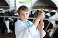 Boy in white robe stands with hayfork near small