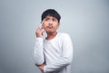 A boy in a white shirt is holding a white pen on a white background. Shows thinking, pondering, and considering options
