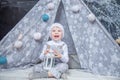 A boy in a white suit sits in a tent