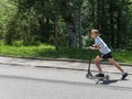 A boy in white T-shirt and dark shorts rides a scooter along the road up. Russia Sochi 08 04 2019