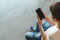 Boy in white T-shirt and sunglasses sitting indoor and uses smartphone. Teenager plays computer games on digital gadget Royalty Free Stock Photo