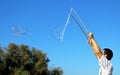 A boy who is making a big soap bubble with two sticks and a rope Royalty Free Stock Photo