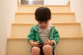 A boy who was scolded by his mother secretly came to play on the phone on the stairs Royalty Free Stock Photo