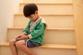 A boy who was scolded by his mother secretly came to play on the phone on the stairs Royalty Free Stock Photo