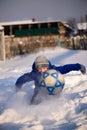 Schoolboy boy kicks the ball playing in winter football on the s