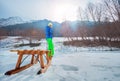 Boy in winter outfit pull wooden sledge uphill turning back Royalty Free Stock Photo
