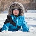 Boy in winterwear laughing while playing in snowdrift outside