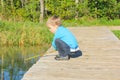 Boy on a wooden bridge is played with a stick in the water. the Royalty Free Stock Photo