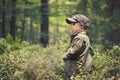 A boy in the woods, standing among trees, stands sidewaysd. Royalty Free Stock Photo