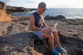 A boy works on the rocks near the ocean using his laptop during sunset Royalty Free Stock Photo