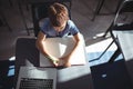 Boy writing in book by laptop at desk