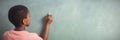 Boy writing with chalk on greenboard in school