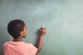 Boy writing with chalk on greenboard in school