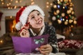 Boy writing letter to Santa Claus in red hat near the Christmas tree Royalty Free Stock Photo