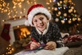 Boy writing letter to Santa Claus in red hat near the Christmas tree Royalty Free Stock Photo