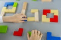 Boy& x27;s hand with a wooden cube on the gray background. Multi-colored cubes on the table. Geometric shapes on a wooden Royalty Free Stock Photo