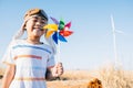 Boy& x27;s playful fascination near wind turbines holding a pinwheel toy Royalty Free Stock Photo