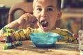 The boy 4 years eats porridge. Children`s table. The concept of the child`s independence. the boy is breakfasting with an appeti