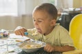 The boy 2 years eats porridge. Children& x27;s table. The concept of the child& x27;s independence. happy little boy eating