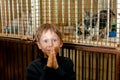 A boy 7-8 years old asks to take a kitten from an animal shelter. In the background are cages with kittens