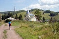 Boy, 12 years old, with a backpack is walking along a dirt road to a church in the village of Parnaya on a summer sunny day.