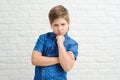 Boy 9-10 years old in a blue shirt on a light background, the emotion of resentment Royalty Free Stock Photo