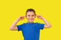 boy 6 years old in blue t-shirt on yellow background, foolish funny emotion expression on face Royalty Free Stock Photo