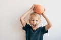Boy of 5-7 years old is fooling around and puts a ripe big pumpkin on his head. Royalty Free Stock Photo
