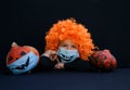 Boy 4 years old in orange wig and pumpkin in blue medical mask with a painted scary smile Royalty Free Stock Photo