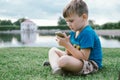 Boy 5 Years Old with smart phone Resting on green grass in park Royalty Free Stock Photo