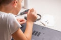 A boy of 10 years old is sorting a laptop for cleaning and maintenance. Selective focus. Screwdrivers, purge cylinder, magnifying Royalty Free Stock Photo