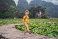 Boy in a yellow on the path among the lotus lake. Mua Cave, Ninh Binh, Vietnam. Vietnam reopens after quarantine