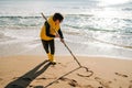 Boy in yellow rubber boots drawing heart shape on sand at the beach. School kid touching water at autumn winter sea Royalty Free Stock Photo