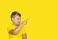 A boy in a yellow T-shirt on a yellow background points his fingers at something. The concept of a banner with information. Space