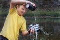 A boy in a yellow T-shirt pours water on a digital SLR camera