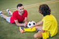 Boy in yellow uniform and his coach having a break after game